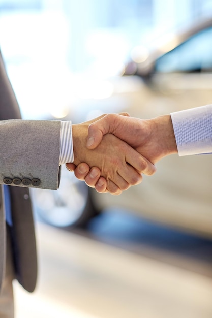 auto business, car sale, deal, gesture and people concept - close up of male handshake in auto show or salon