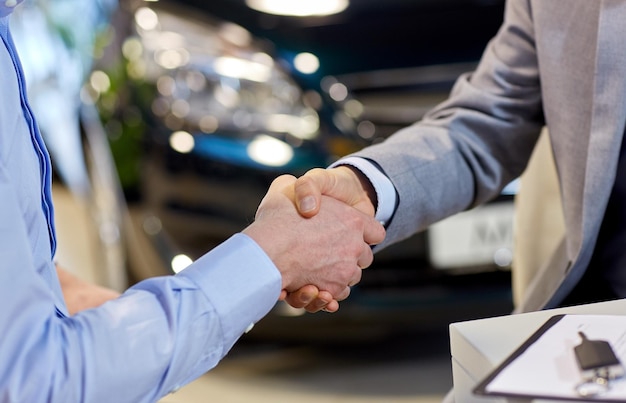 auto business, car sale, deal, gesture and people concept - close up of male handshake in auto show or salon