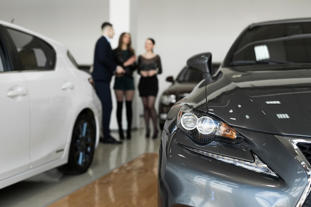 Auto business, car sales - a couple of friends of girls with a car dealer choose a car in a car dealership