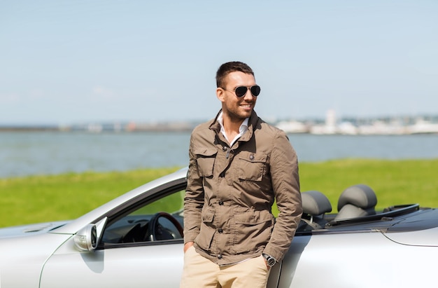 auto business, transport, leisure and people concept - happy man near cabriolet car outdoors