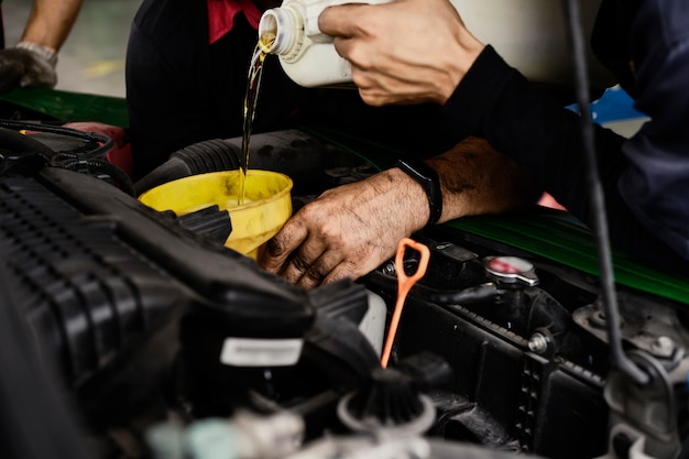 Auto mechanic changing oil machine.    The man is changing the motor oil.Change engine oil.Replacement of automobile oil.Check the auto maintenance.transportation repair service center