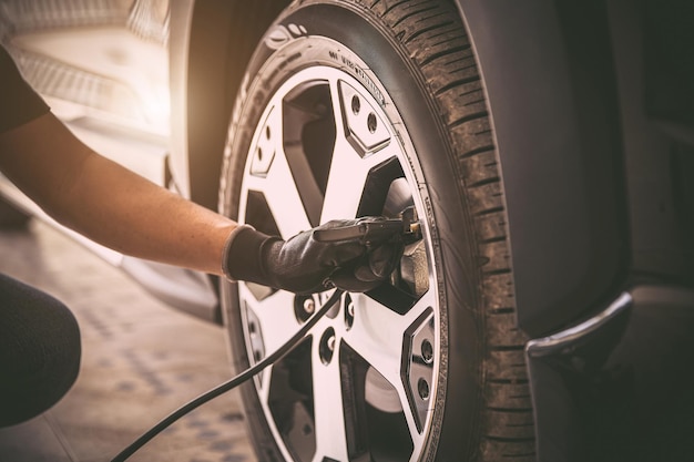 Auto mechanic checking air pressure and inflating car tires Concept of car care service and maintenance