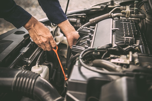 Auto mechanic checking vehicle engine oil level.