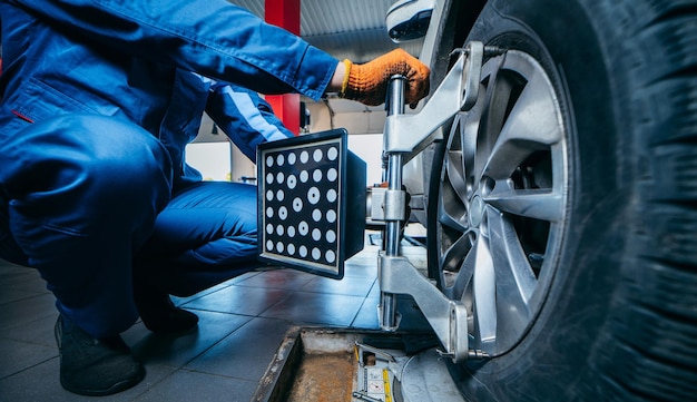 Auto mechanic installing sensor during suspension adjustment and automobile wheel alignment work