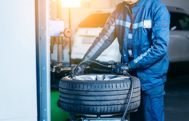 Photo auto mechanic making car tire pressure check on the removed wheel in the auto service garage