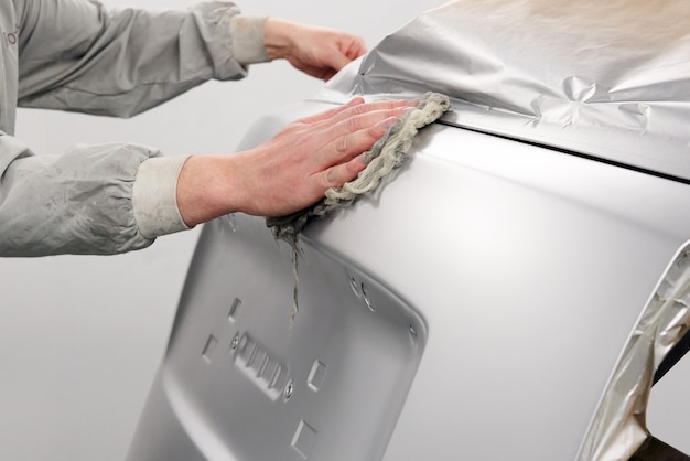 Auto mechanic preparing the car for paint job in painting booth in auto repair shop