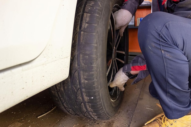 Auto mechanic in the process of replacing new tires Repair of car brakes in the garage