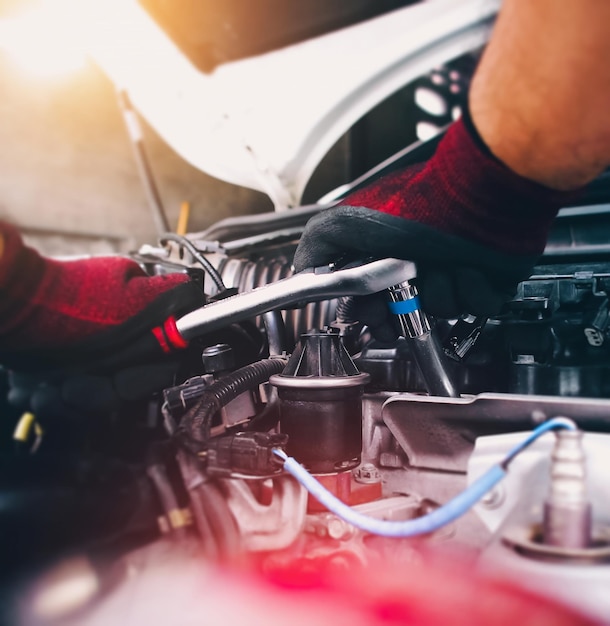 Auto mechanic repairing engine with socket wrench in the auto repair garage automotive maintenance service concept