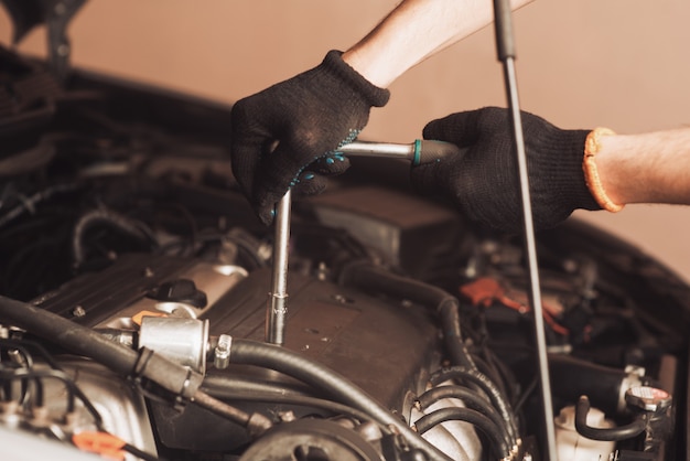 Photo auto mechanic repairs car. the employee carries out maintenance of the machine.