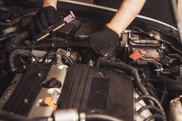 Photo auto mechanic repairs car. the employee carries out maintenance of the machine.