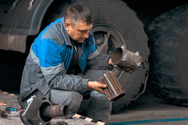 Auto mechanic repairs truck Professional repair and diagnostics of cargo tractors and equipment Mechanic in workshop considers spare parts