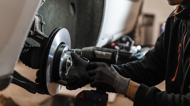 An auto mechanic at a service station changes the brake discs and brake pads to new ones for a car