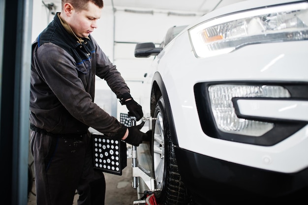 Auto mechanic sets american SUV car for diagnostics and configuration camber check in workshop of service station