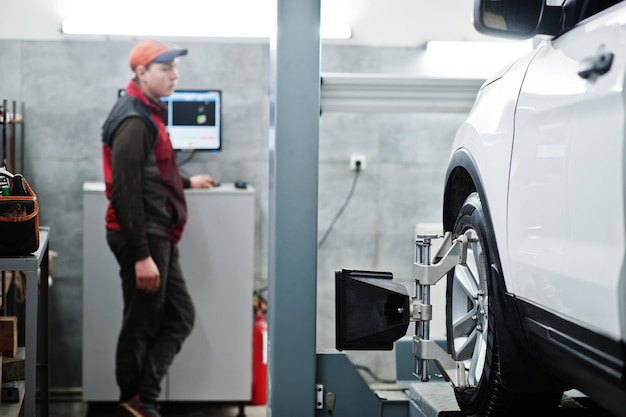 Auto mechanic sets american SUV car for diagnostics and configuration camber check in workshop of service station