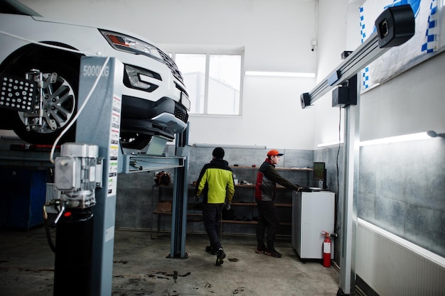 Auto mechanic sets american SUV car for diagnostics and configuration camber check in workshop of service station