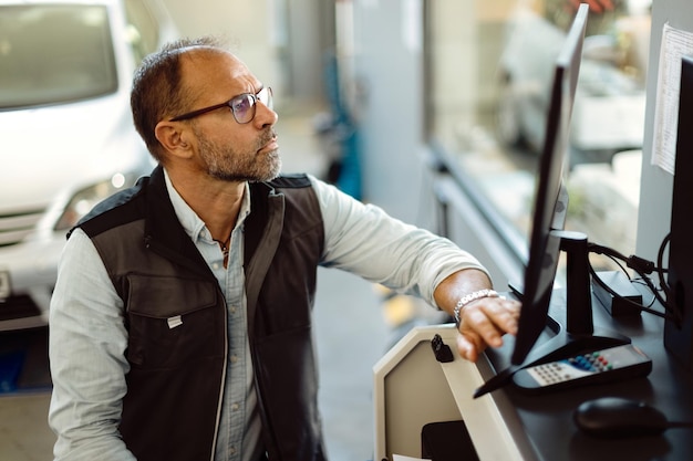 Auto mechanic using computer while working at car service shop