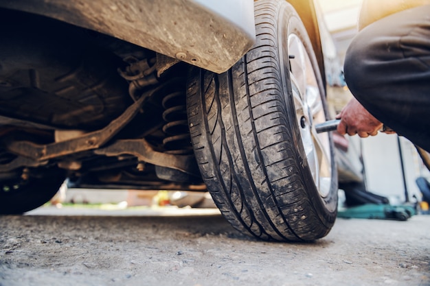 Auto mechanic using tool to change tire while crouching at workshop.