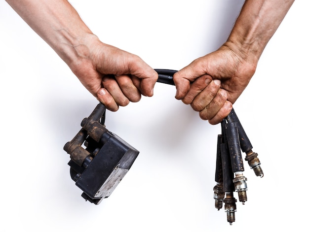 Auto mechanic with old high-voltage wires, spark plugs and ignition coil