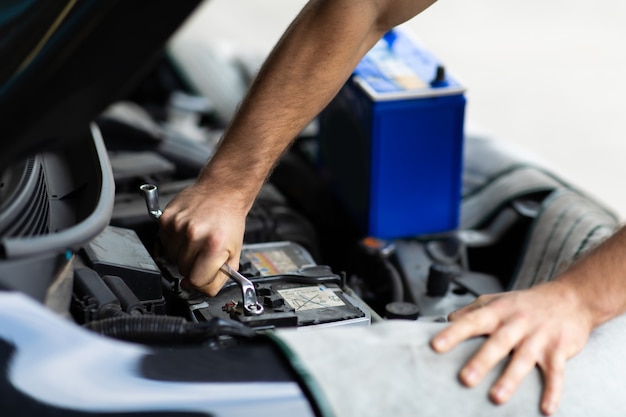 Auto mechanic worker checking and changing car battery. Car maintenance and auto service garage concept.