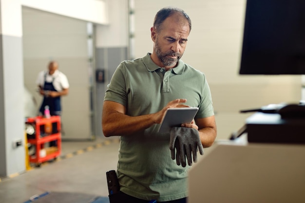 Auto mechanic working on digital tablet at repair shop