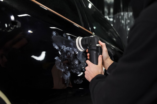 Auto polishing process. Detailing worker polishes car body