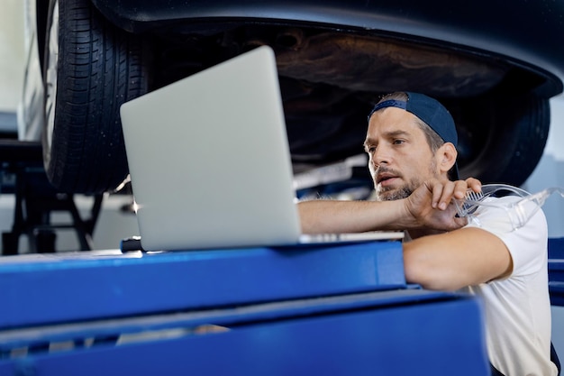 Auto repairman using computer while working in a workshop