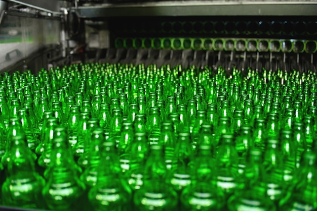 Automated conveyor line in a brewery. Rows of green glass bottles on the conveyor close-up.