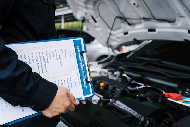 Photo automobile mechanic repairman checking a car engine by inspecting and writing to the clipboard the checklist for repair machine and car service for maintenance and maintenance check concept