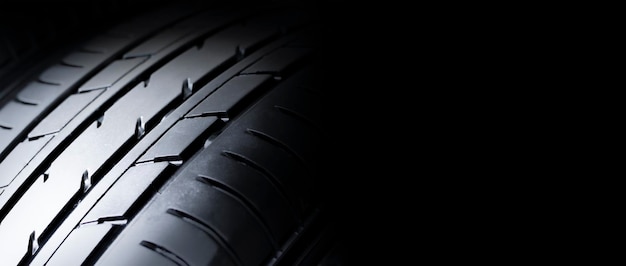 Automobile tire tread with a depth and light in the darkness selective focus and panoramic banner copy space on black background