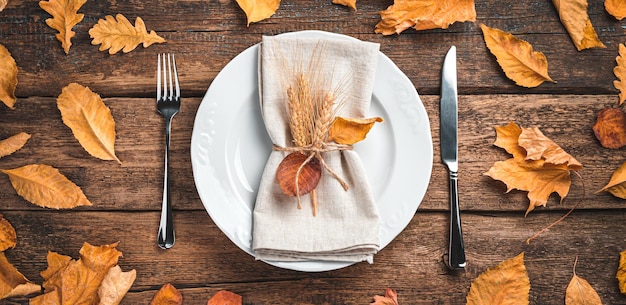 Autumn background with cutlery dishes and autumn leaves on a wooden background