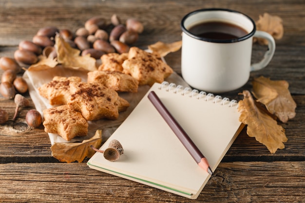 Autumn background with leaves of maple and Acorns a on wooden background. paper with a pencil in the autumn background, place for text