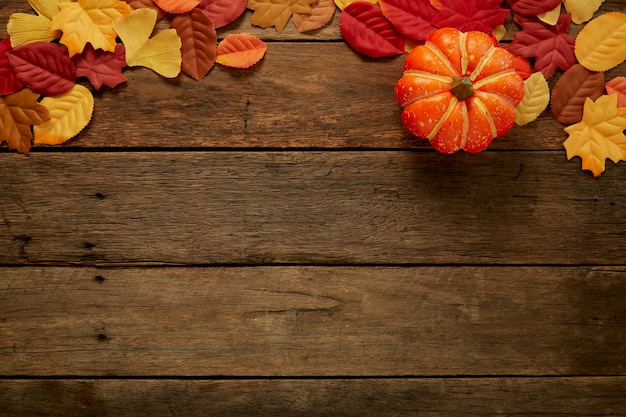 Autumn background with leaves and pumpkins on dark wooden