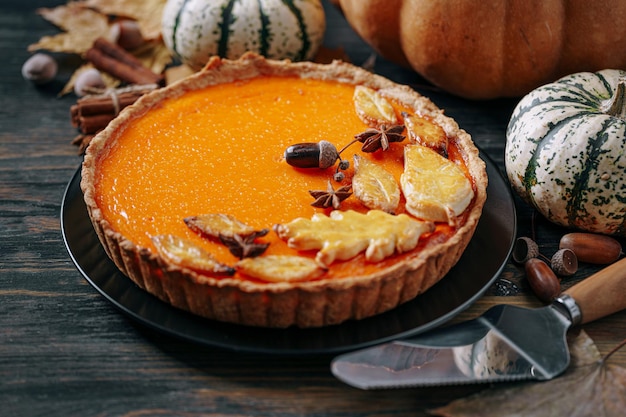 Autumn baking background with pumpkin pie pumpkin yellow autumn leaves on wooden background