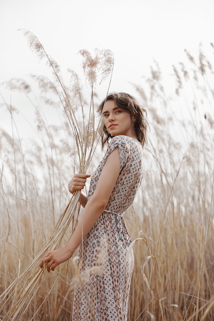 Autumn beauty portrait of a beautiful girl in a field in the grass rays of the sunset. 