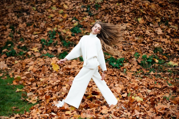 Autumn beauty Woman fashion wodel with fall maple leaf outdoorsy full length in motion Autumnal vogue