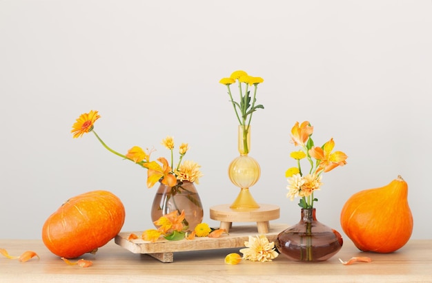 Photo autumn bouquet and orange pumpkins on wooden shelf on background gray wall