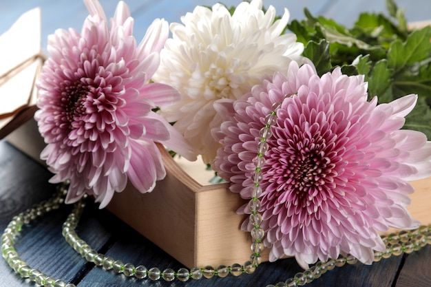 Autumn chrysanthemum flowers with beads and letters on a dark blue table