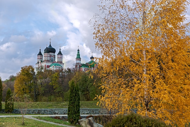 Autumn city park with views of the church and the surface of the lake with a long alley