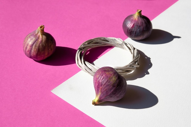 Autumn colors Purple and magenta fig fruits on vibrant fuchsia and white geometric layered paper