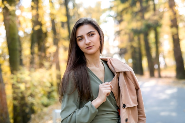 Autumn colours. Beautiful woman in coat posing in forest on roadside