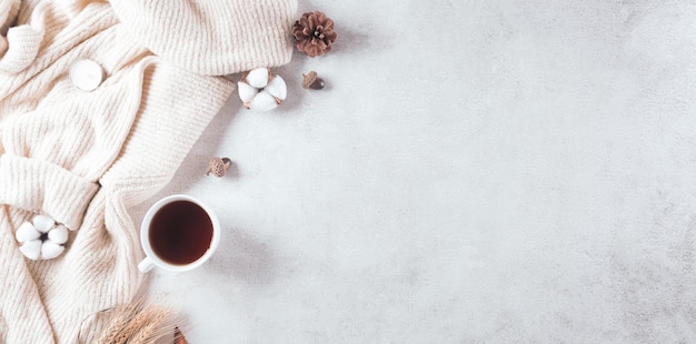 Autumn composition A cup of coffee cotton flowers autumn leaves and sweater on stone background Flat lay top view with copy space