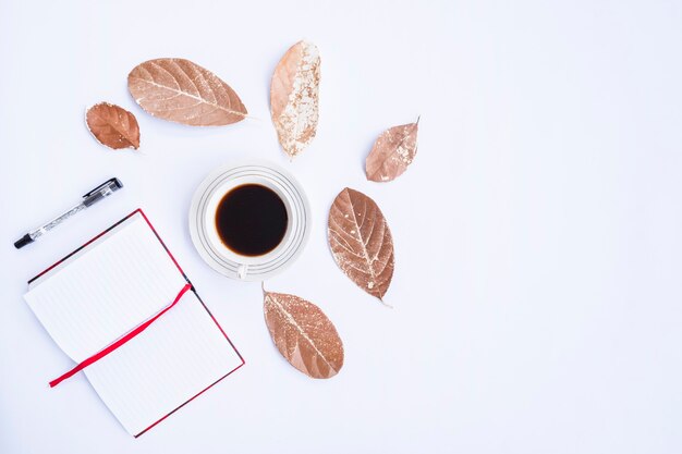 Autumn composition. Cup of coffee, dry leaves, book and pen on white background. Autumn, autumn concept. Flat lay, top view, copy space