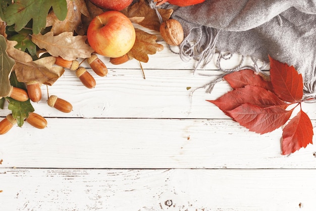 Autumn composition of dry leaves apples and acorns on a white wooden table Top view Copy space