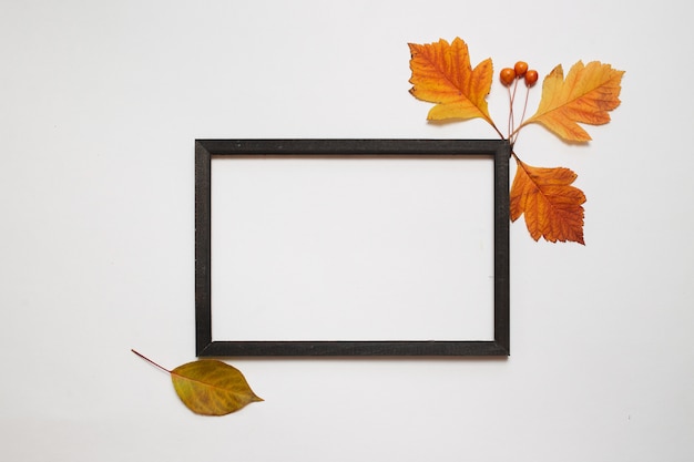 Autumn composition, Flat lay. Wooden photo frame with fresh autumn leaves on white background