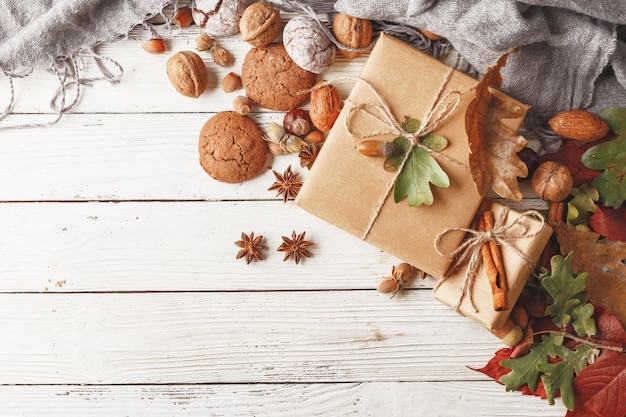 Autumn composition Gift box autumn leaves fruits and spices on a white wooden table Top view Copy space