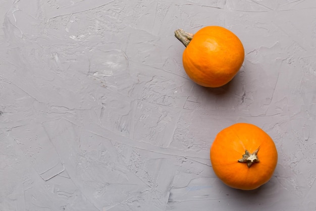 Autumn composition of little orange pumpkins on colored table background Fall Halloween and Thanksgiving concept Autumn flat lay photography Top view vith copy space