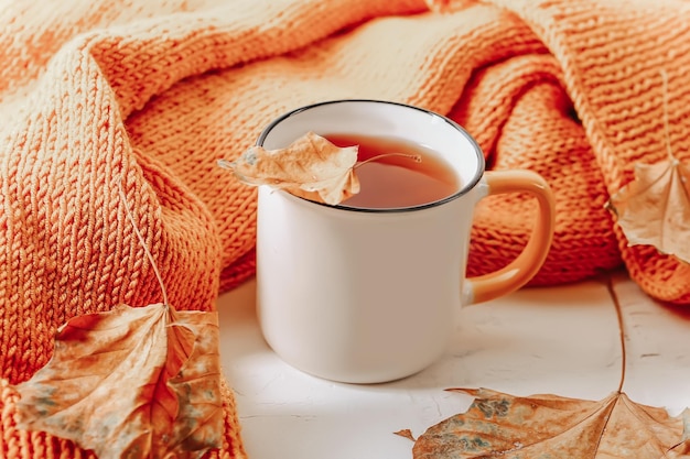 Autumn composition Orange knitted sweater with a cup of tea and autumn leaves