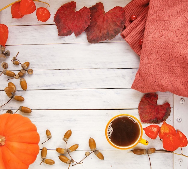 Autumn composition pumpkin with a cup of tea autumn leaves acorns and a knitted sweater