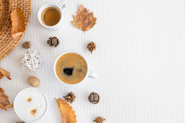 Autumn composition with cups of coffee and leaves on a white background