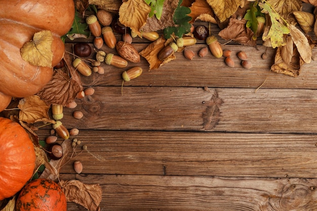 Autumn composition with dry leaves and ripe pumpkins on a wooden table Top view Copy space